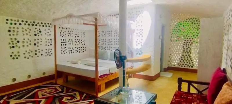 Une chambre lumineuse avec un lit à baldaquin et une décoration murale originale.