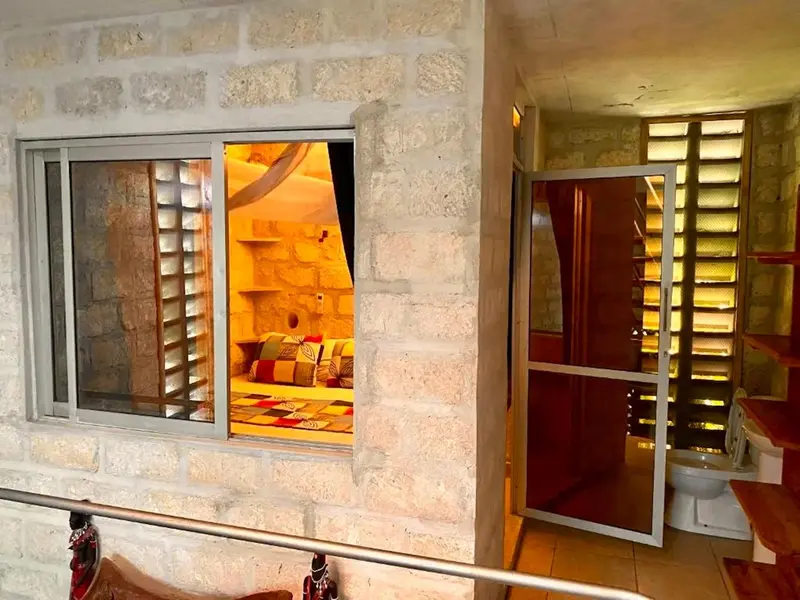 Une chambre lumineuse avec un lit coloré et une kitchenette.