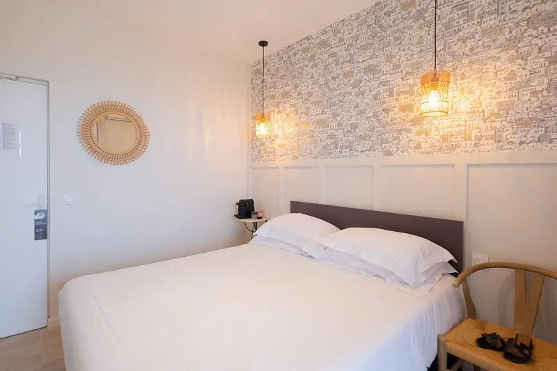 Une chambre lumineuse avec un lit blanc et un décor mural.
