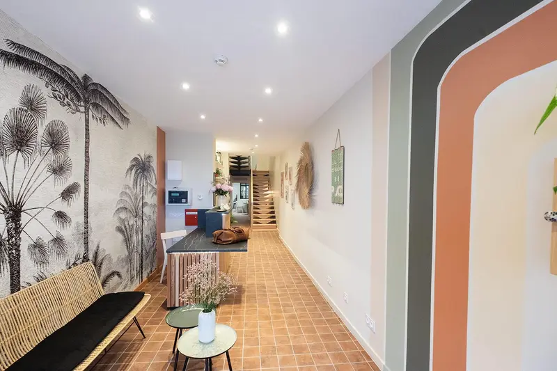 Un couloir lumineux mène vers un espace de réception décoré de motifs végétaux.