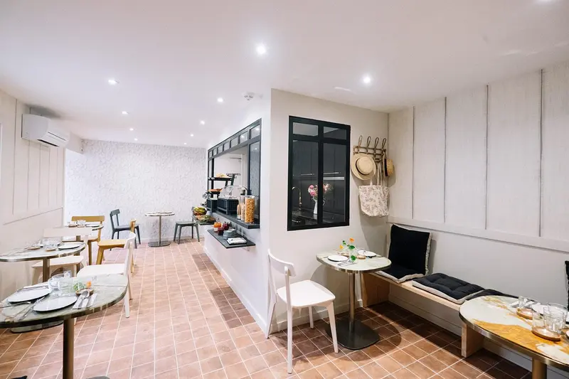 Une salle lumineuse avec des tables et des chaises pour le petit-déjeuner.