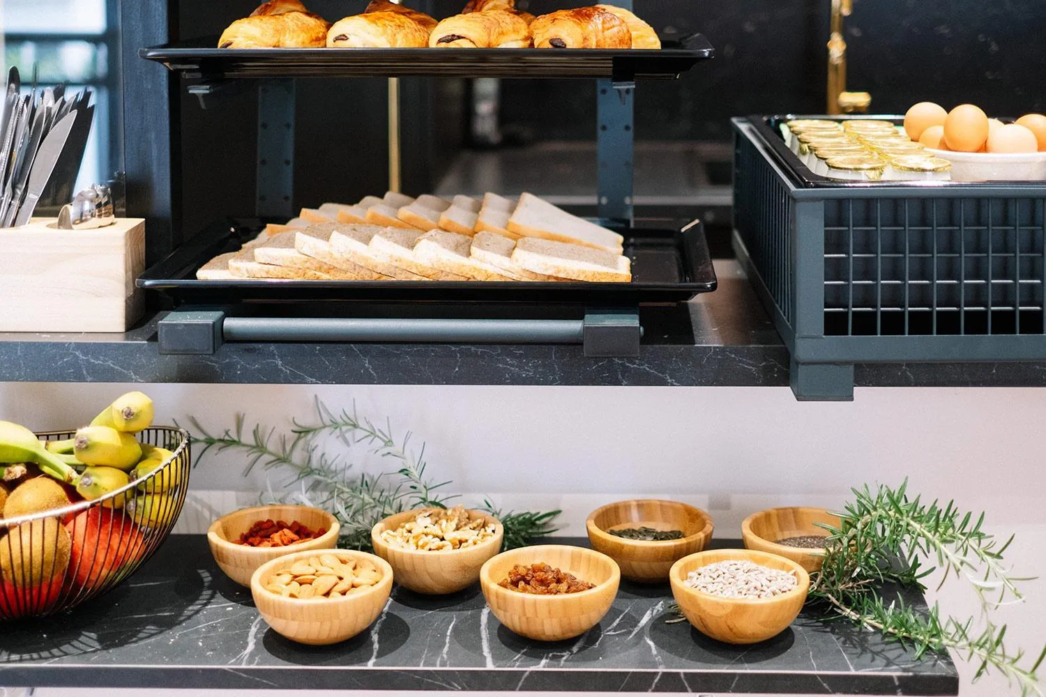 Présentation de viennoiseries, de pains et de fruits secs sur un buffet.