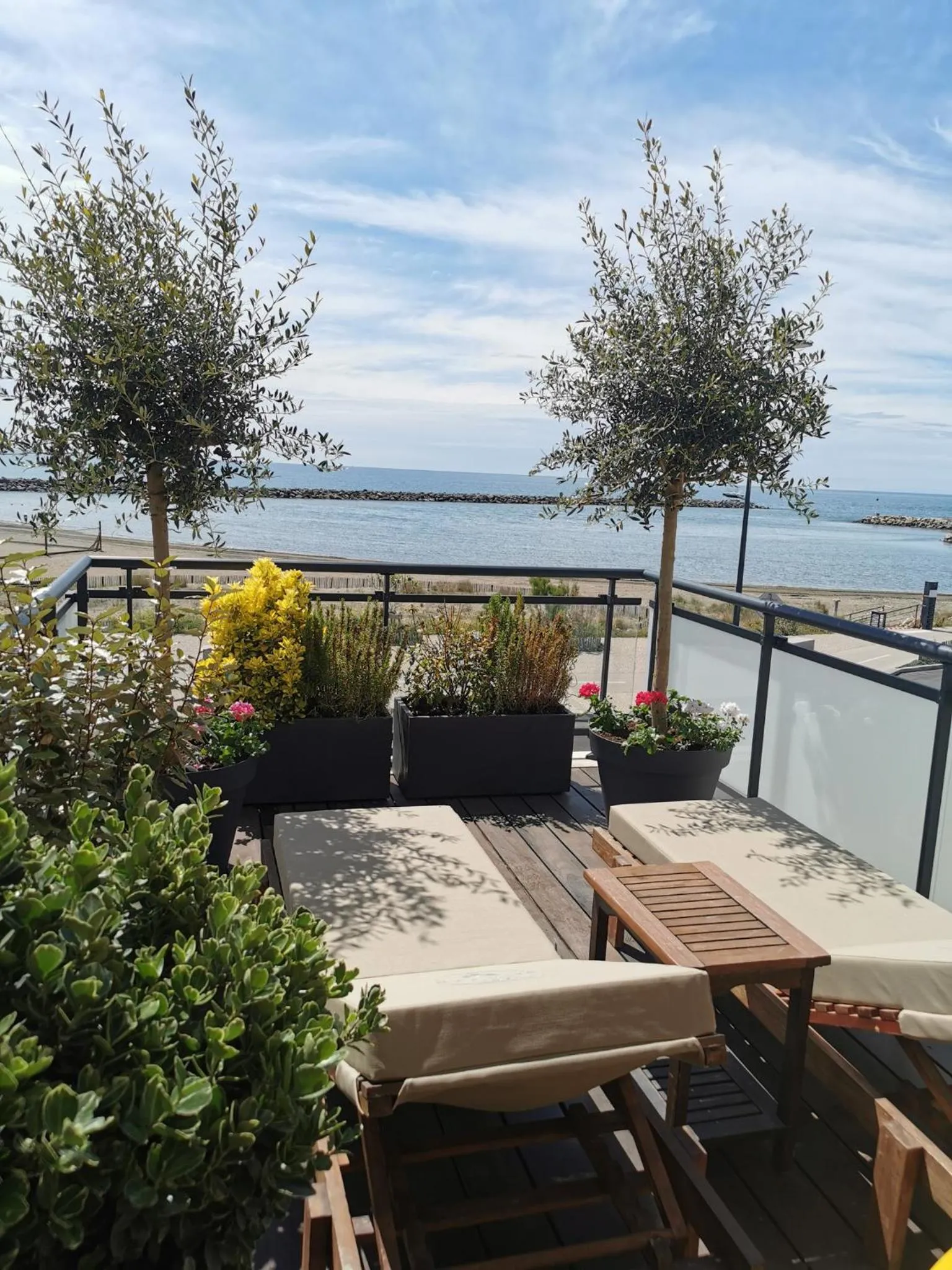 Terrasse aménagée avec mobilier de jardin et vue sur la mer.
