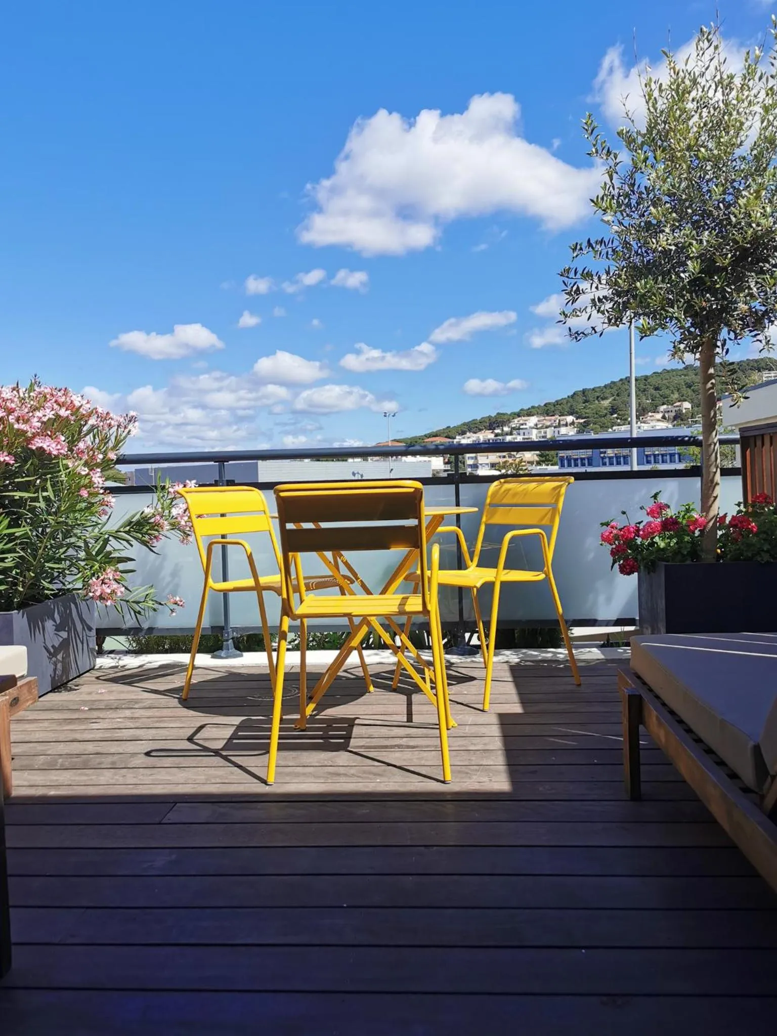 Terrasse ensoleillée avec mobilier jaune et vue sur la mer.