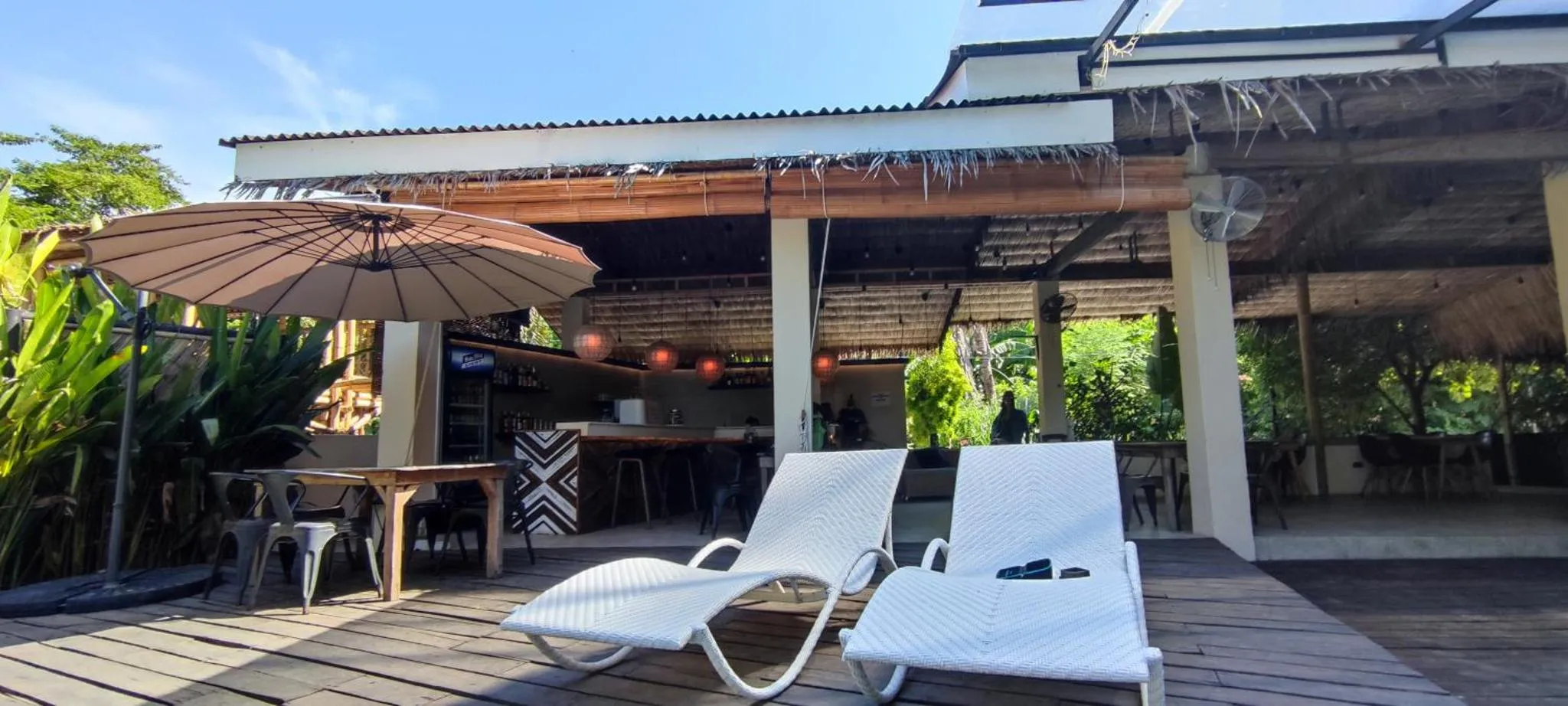 Terrasse ombragée avec mobilier de détente et bar en fond.