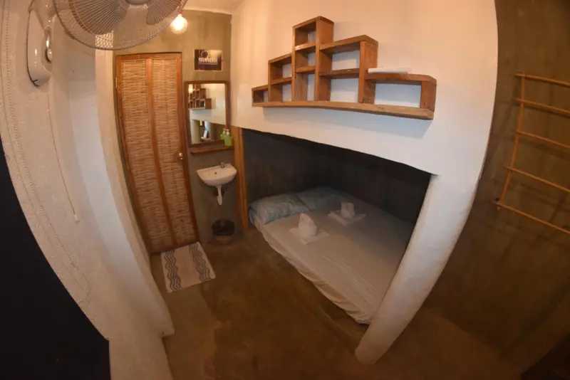 Une chambre sobre avec un lit encastré et des étagères murales.