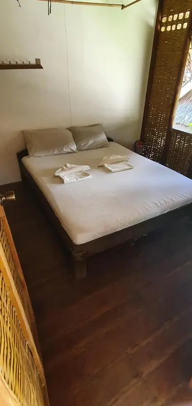 Lit simple dans une chambre rustique avec moustiquaire.
