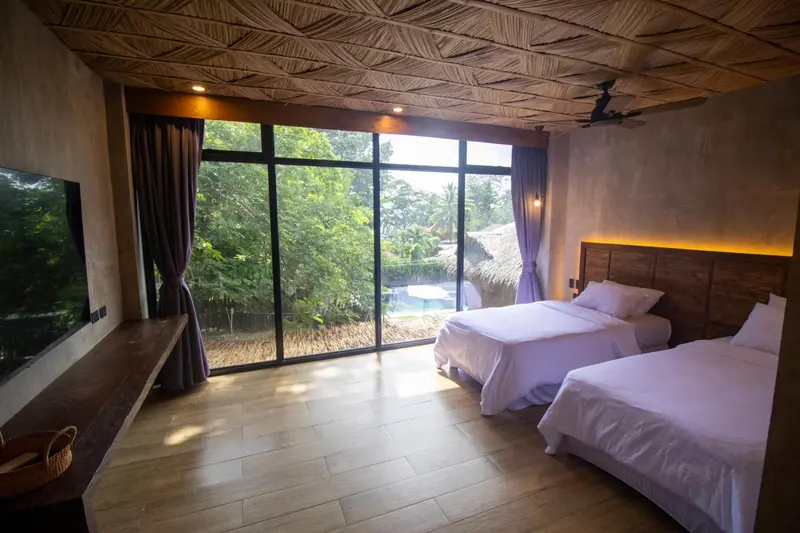 Une chambre lumineuse avec un grand lit et une vue sur la végétation et une piscine.