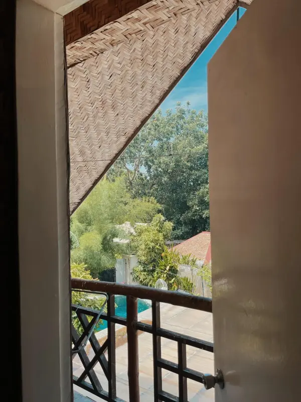 Vue sur une végétation luxuriante et une piscine depuis un balcon.