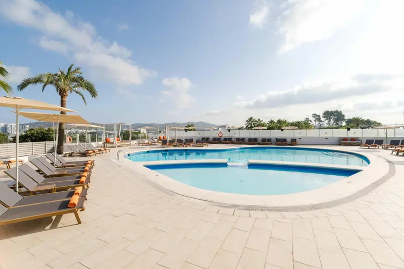 Terrasse avec transats et piscine au bord d'une vue sur la mer.