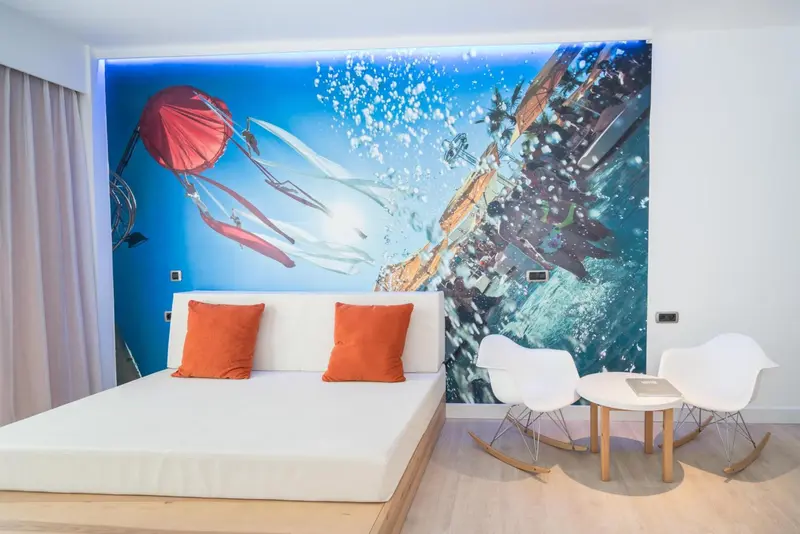 Une chambre lumineuse avec un grand lit et deux fauteuils design.