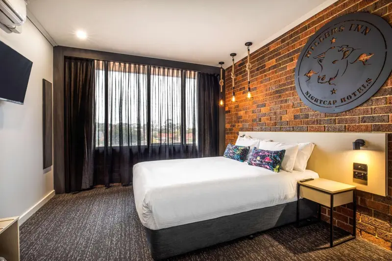 Une chambre d'hôtel moderne avec un grand lit et des rideaux blancs.