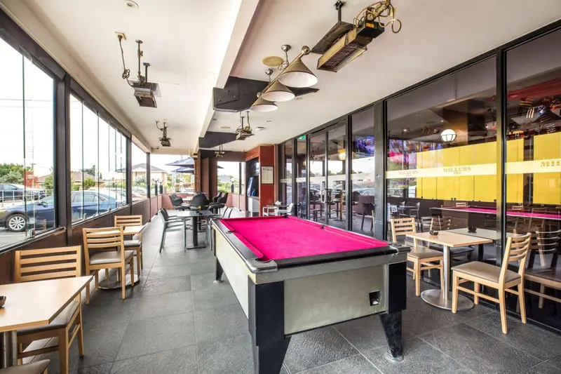 Une salle de jeux avec tables et billard, ouverte sur l'extérieur.