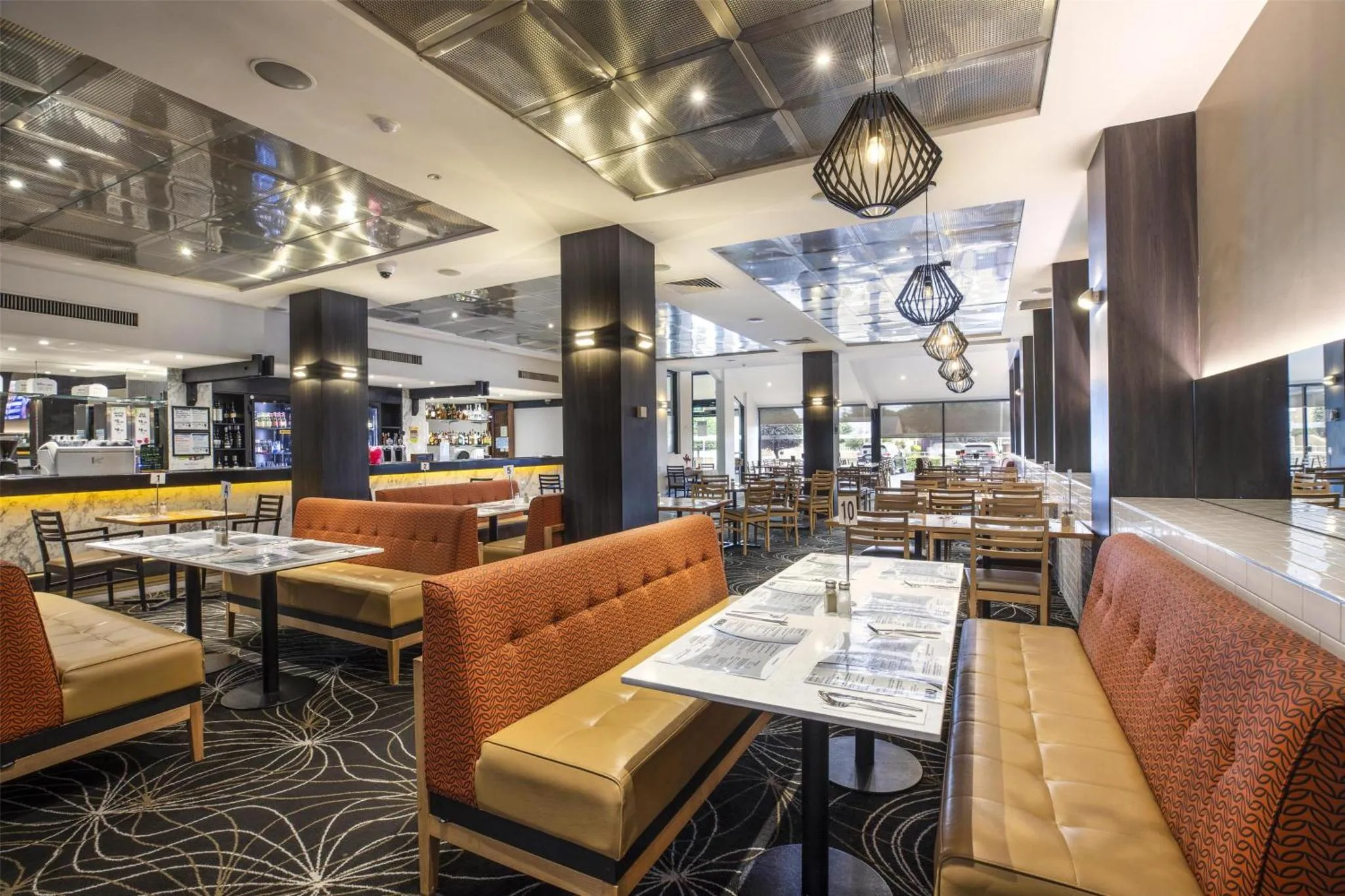 Une salle de restaurant lumineuse avec des tables et des banquettes.