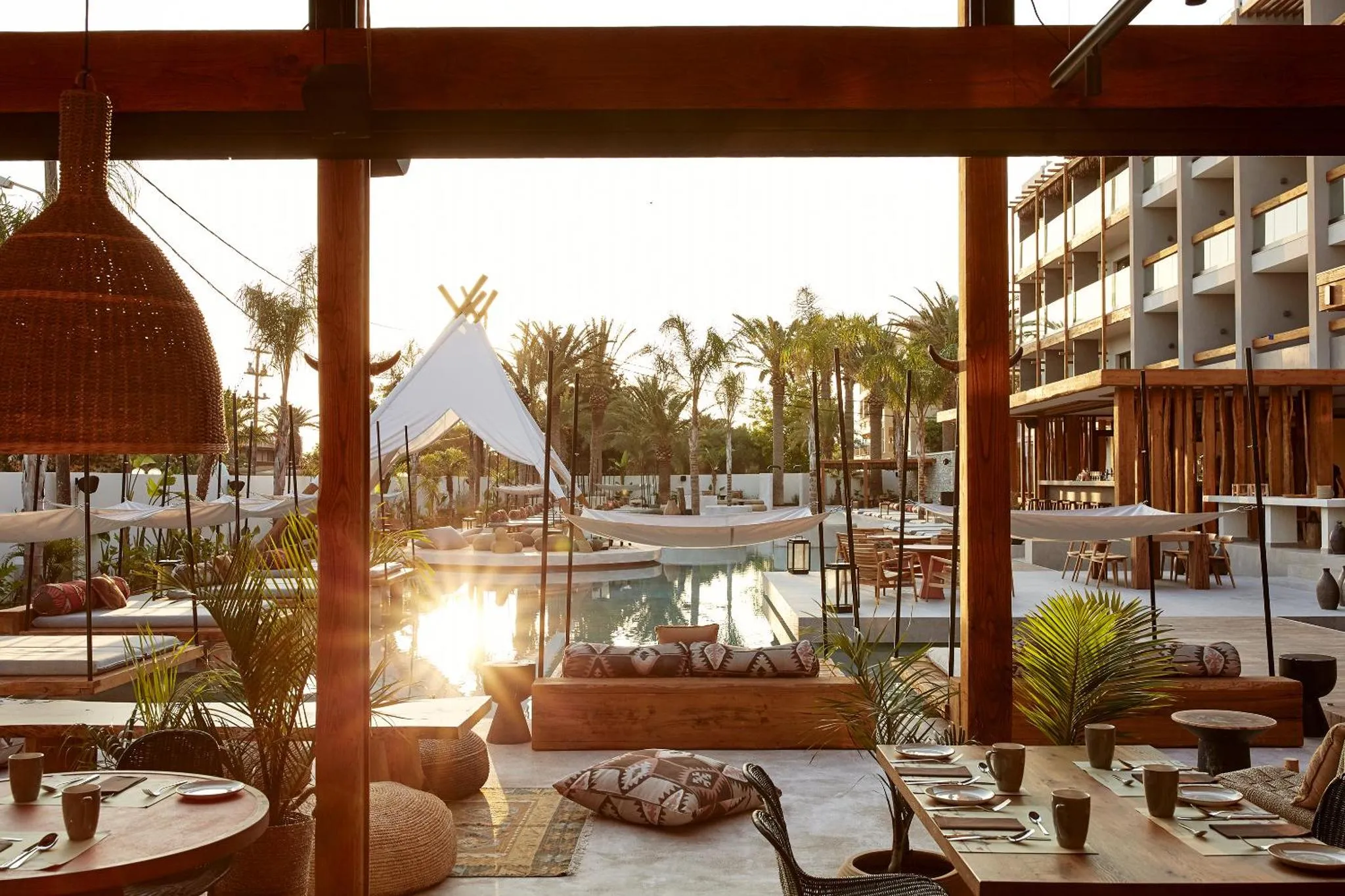 Terrasse ombragée donnant sur une piscine et des bâtiments.
