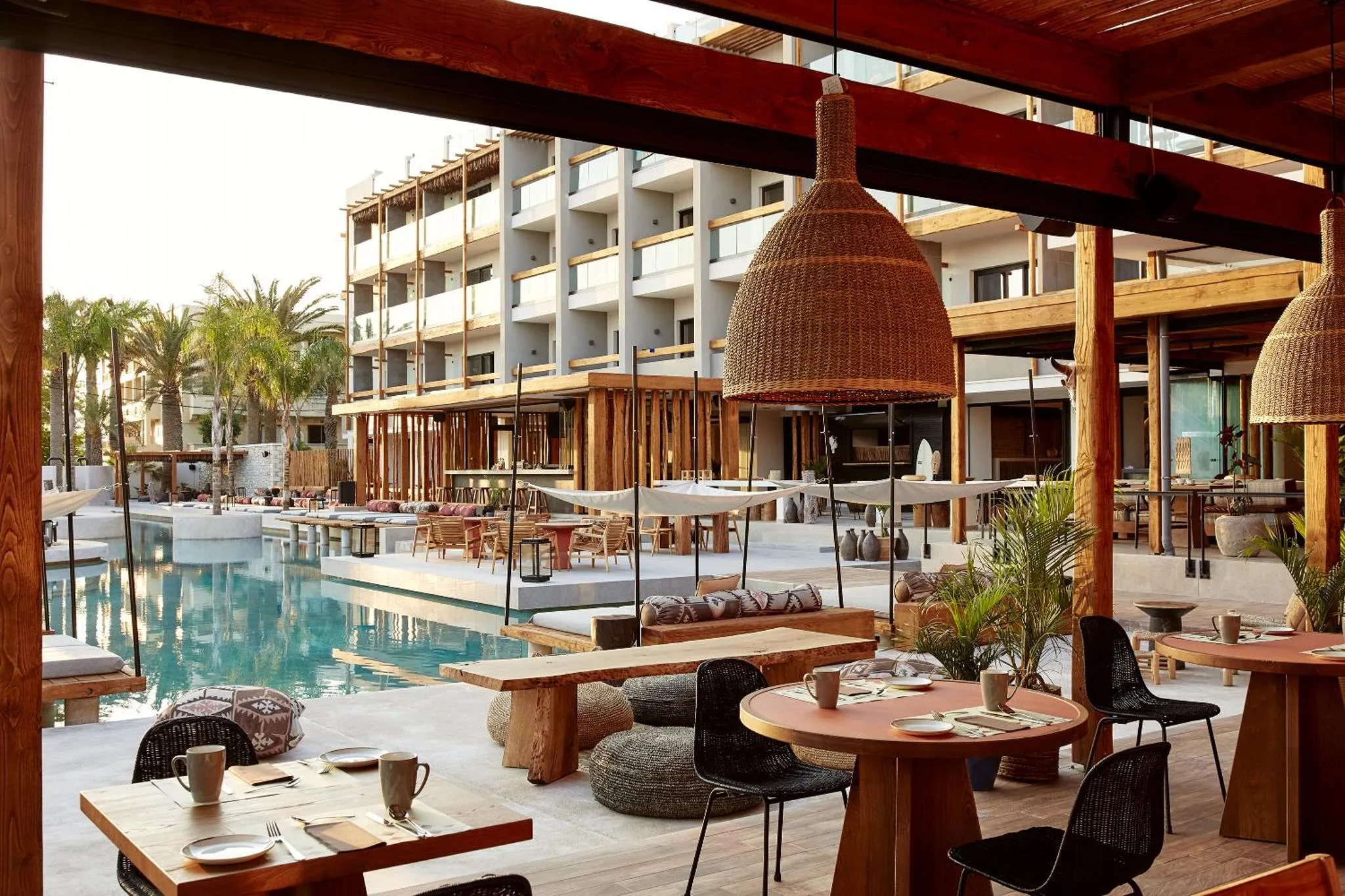 Terrasse ombragée avec tables et chaises près d'une piscine.