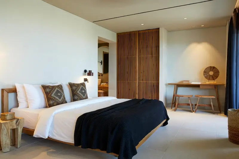 Une chambre lumineuse avec un grand lit et un bureau en bois.