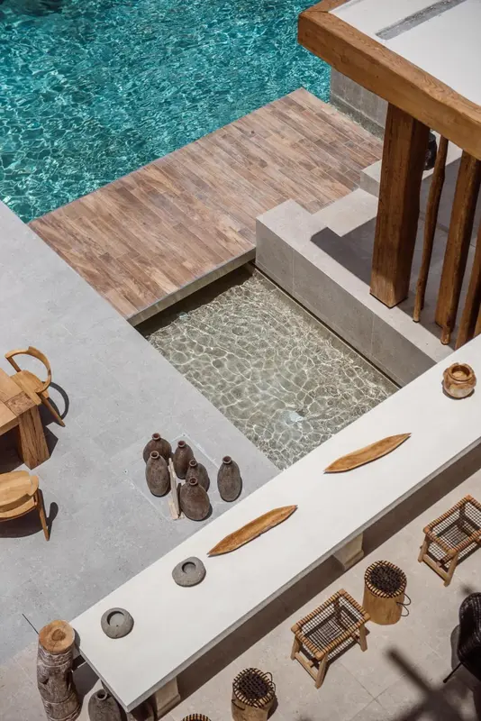 Terrasse en bois blanc avec des pots en céramique et une piscine turquoise.