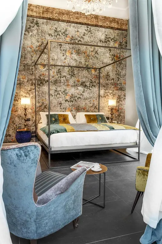 Une chambre avec un lit à baldaquin et un décor floral mural.