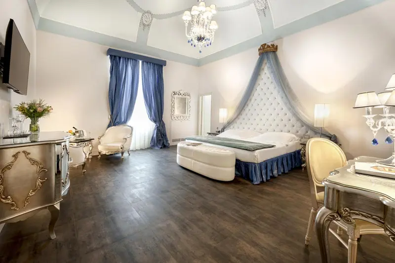 Chambre spacieuse avec un grand lit à baldaquin et un mobilier doré.