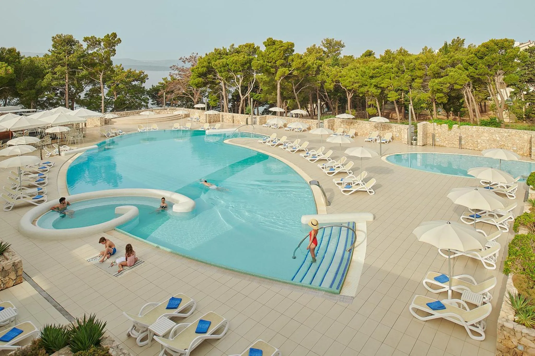 Une piscine avec des transats et des parasols en bord de mer.