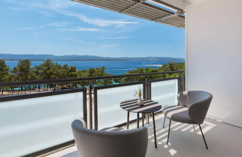 Vue dégagée sur la mer depuis une terrasse aménagée avec des fauteuils et une table.