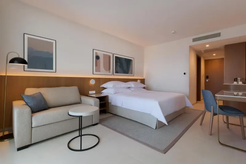 Une chambre lumineuse avec un lit double, un canapé et une table.
