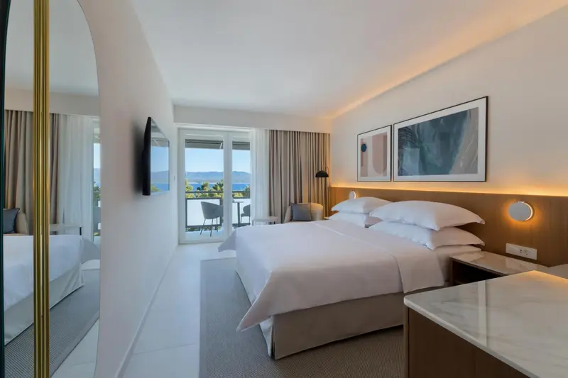 Chambre lumineuse avec un grand lit et une vue sur la mer.