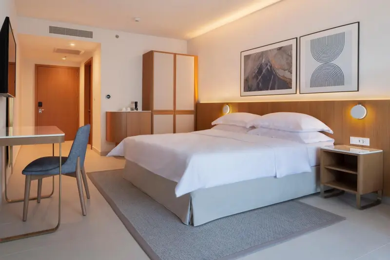 Une chambre lumineuse avec un grand lit et un bureau.