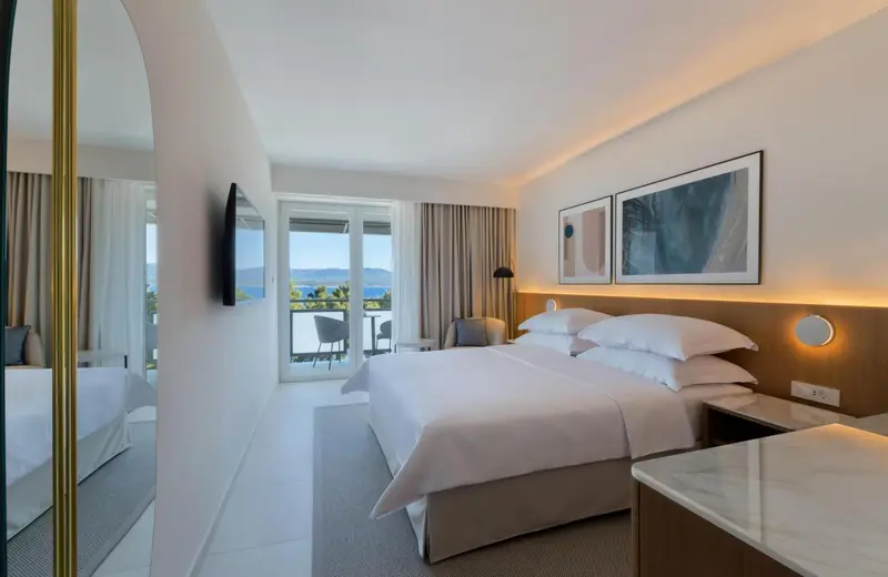 Chambre lumineuse avec un grand lit et une vue sur la mer.