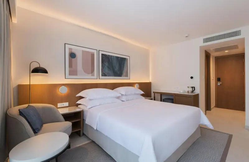 Une chambre d'hôtel moderne avec un grand lit et un fauteuil.
