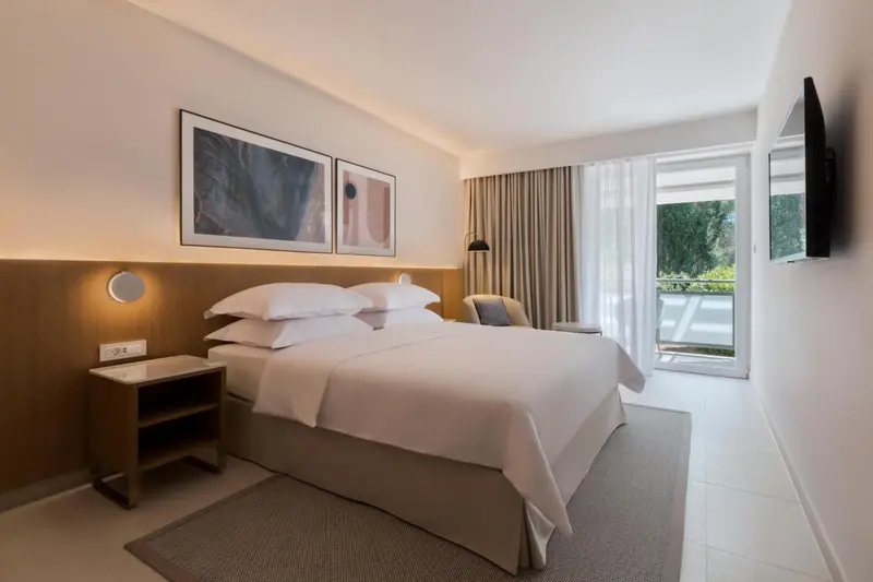 Une chambre lumineuse avec un grand lit et un accès à un balcon.