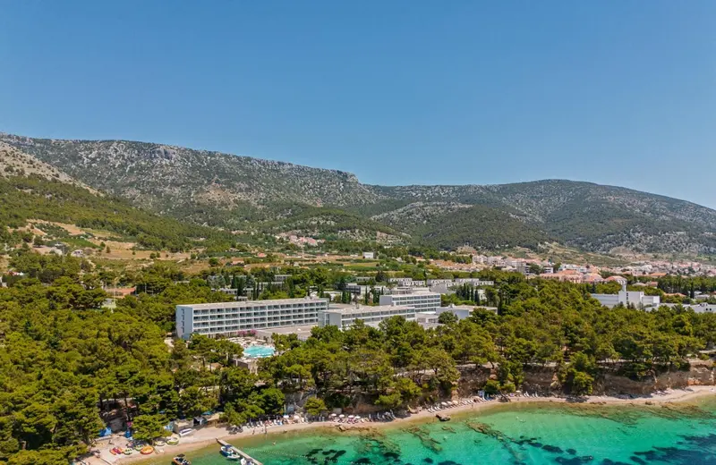 Vue aérienne d'un bâtiment blanc bordant une plage de sable et une mer turquoise.