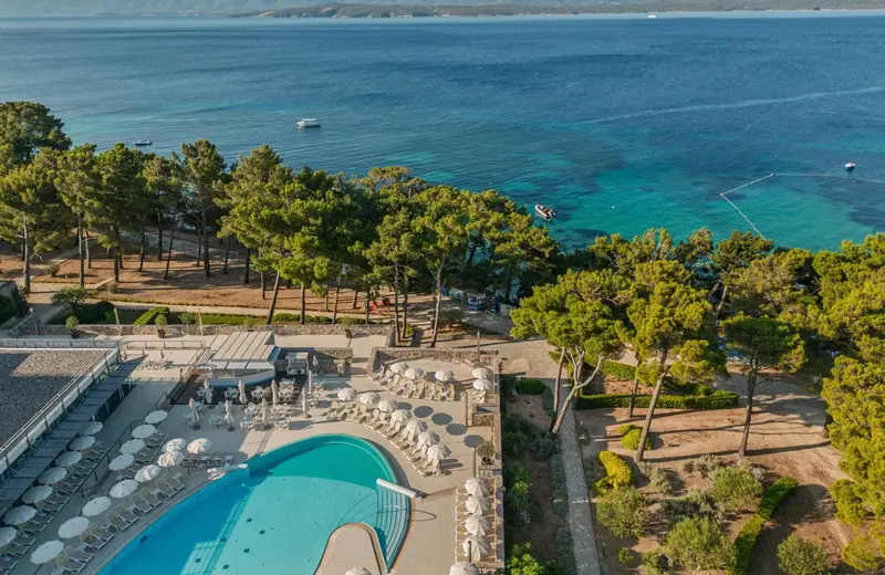 Vue aérienne d'un complexe hôtelier avec piscine et accès à la mer.