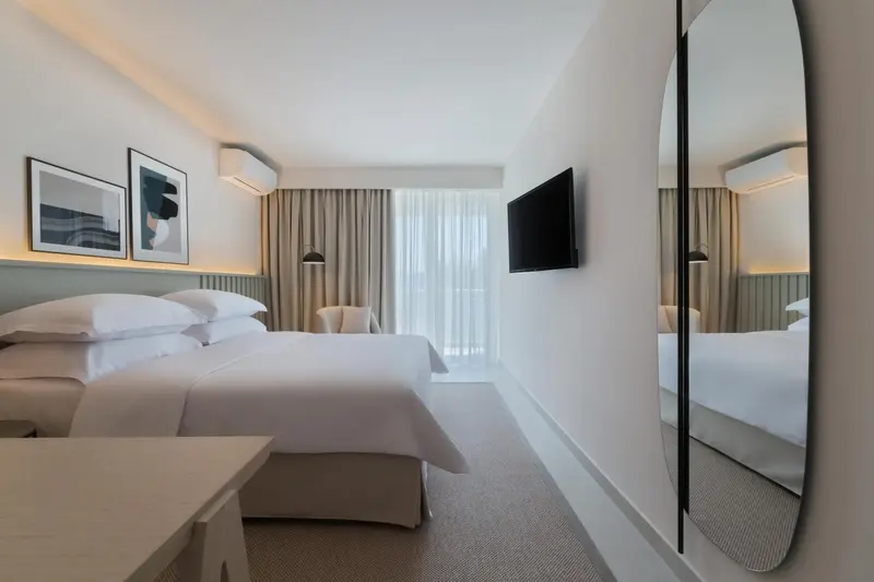 Une chambre lumineuse avec un grand lit et un miroir mural.