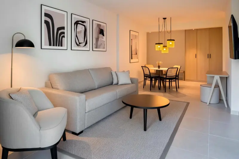 Un salon lumineux avec canapé, fauteuil et table basse.