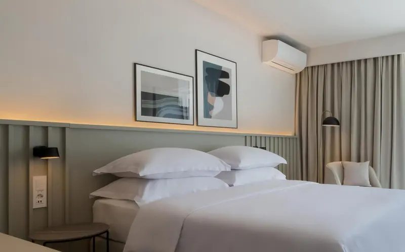 Un lit double avec des oreillers blancs dans une chambre lumineuse.