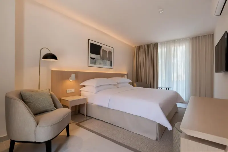 Une chambre lumineuse avec un grand lit et un fauteuil.