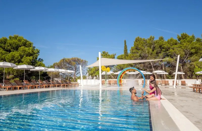 Une famille profite d'une aire de jeux aquatique près d'une piscine.