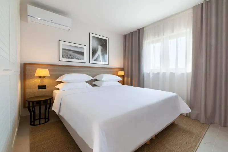 Une chambre lumineuse avec un grand lit recouvert de draps blancs.