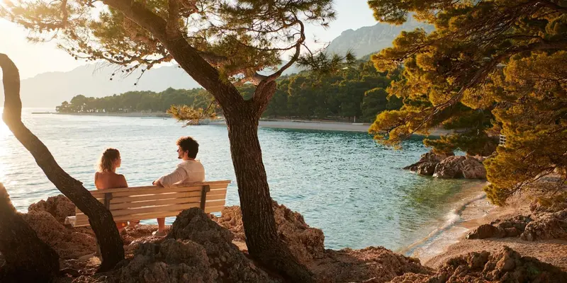 Deux personnes assises sur un banc face à la mer.