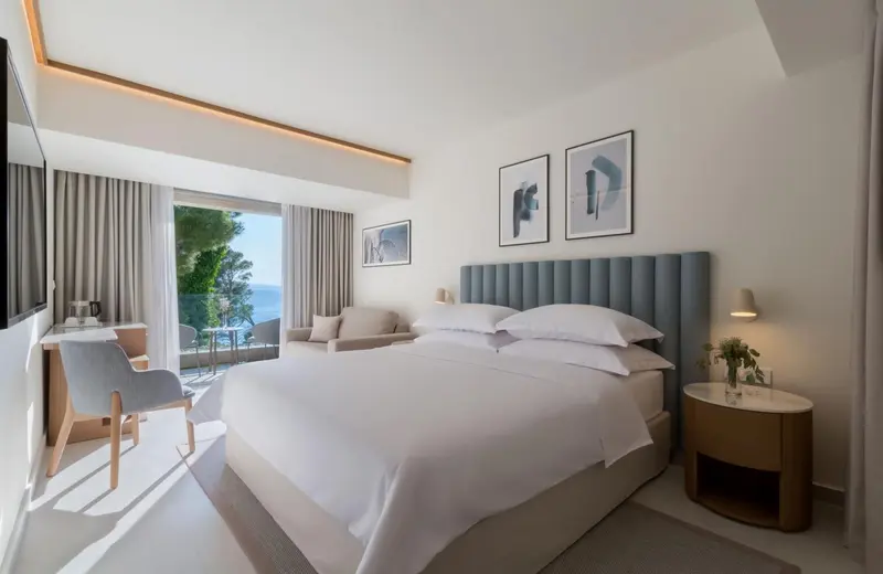 Chambre lumineuse avec un grand lit et une vue sur la mer.