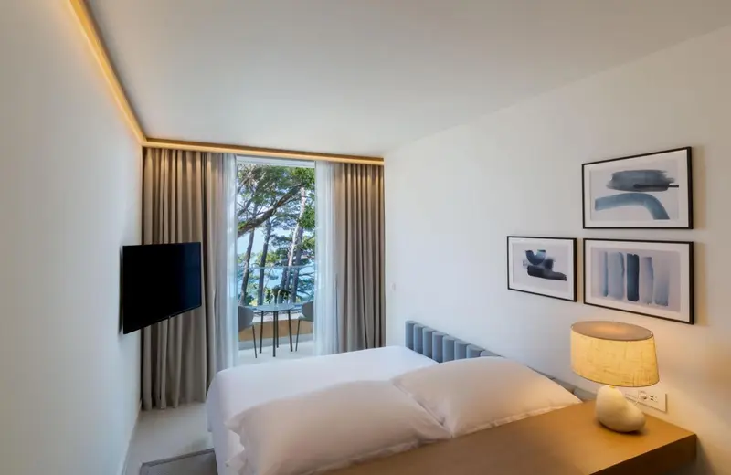 Chambre lumineuse avec un lit blanc et une vue sur la mer.