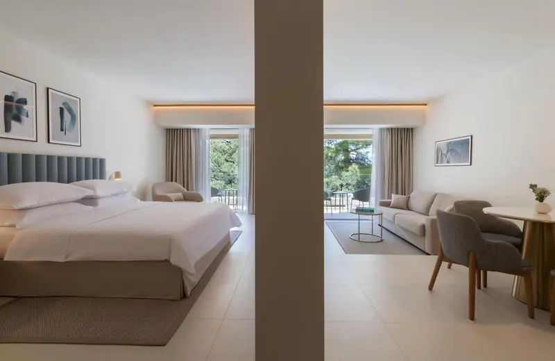 Chambre lumineuse avec un grand lit et un espace salon.