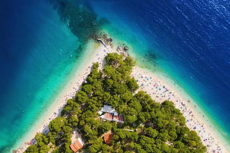 Vue aérienne d'une crique abritée avec une plage de sable et une végétation luxuriante.
