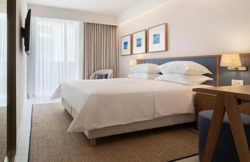 Une chambre lumineuse avec un grand lit et des tableaux décoratifs.
