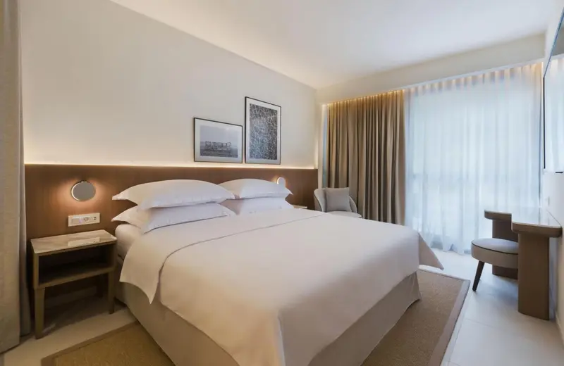 Une chambre lumineuse avec un grand lit et un bureau.