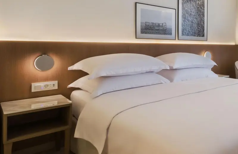 Lit double avec oreillers blancs dans une chambre lumineuse.