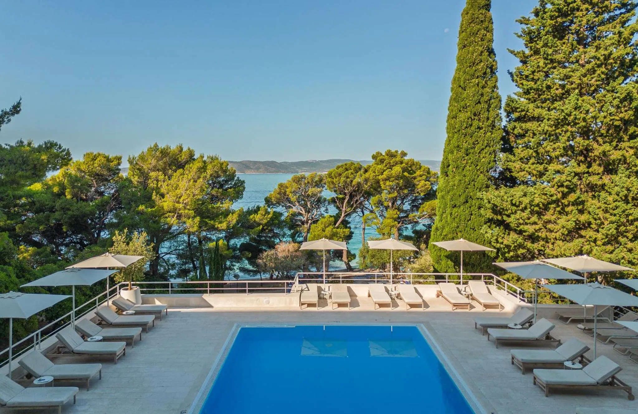 Terrasse avec transats et piscine donnant sur la mer.