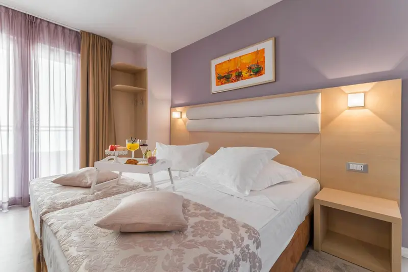 Une chambre d'hôtel avec un lit préparé et un plateau de petit-déjeuner.